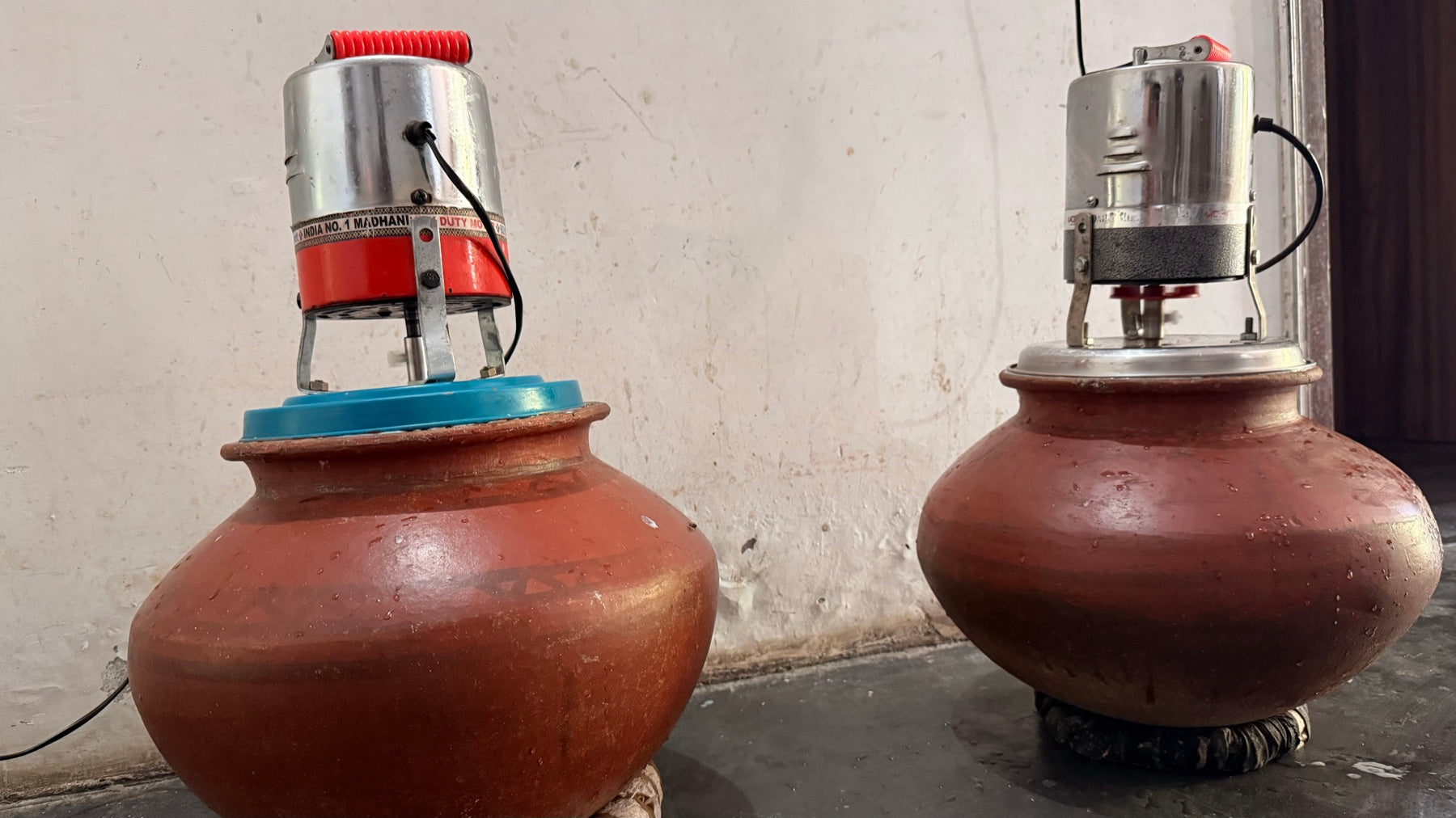 Two clay matka pots with bilona churners used to hand-churn curd into desi ghee at Chahal Agri Farms