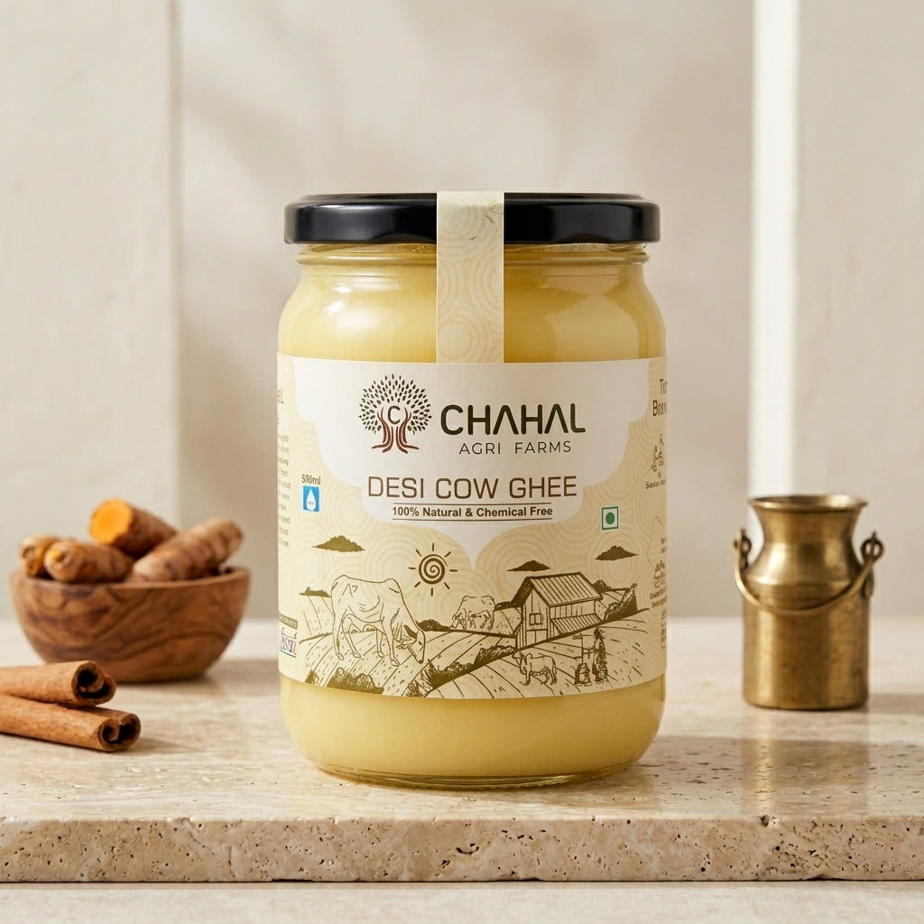 Chahal Agri Farms desi cow ghee glass jar on a stone counter with turmeric root, cinnamon and a brass milk pot