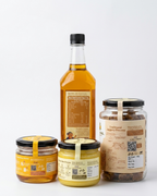 Pure Pantry Starter Box contents — wood-pressed mustard oil, desi cow ghee, wild forest honey and natural jaggery, back labels with nutrition panels